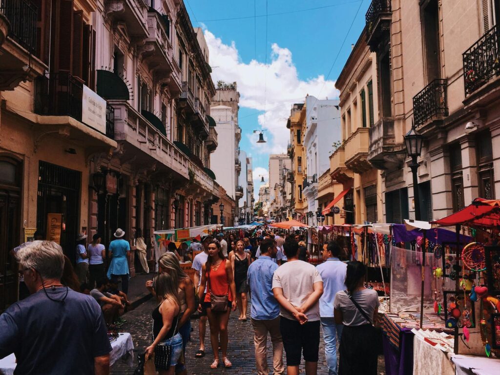 people standing on road beside market and high rise buildings