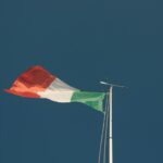 Bandeira italiana tremula contra um céu azul. A foto simboliza a disputa nos tribunais quanto ao massacre nazista de 1943.