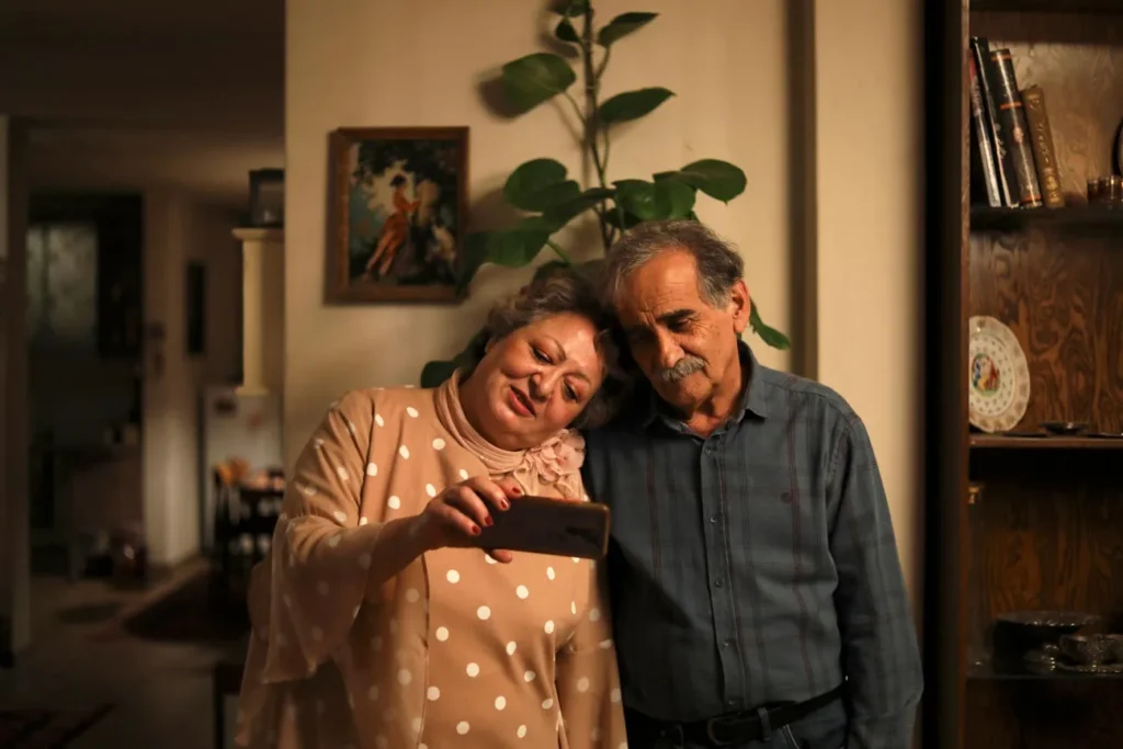 Protagonistas estão um ao lado do outro dentro de casa tirando uma foto no celular, cena bonita de Meu bolo favorito.