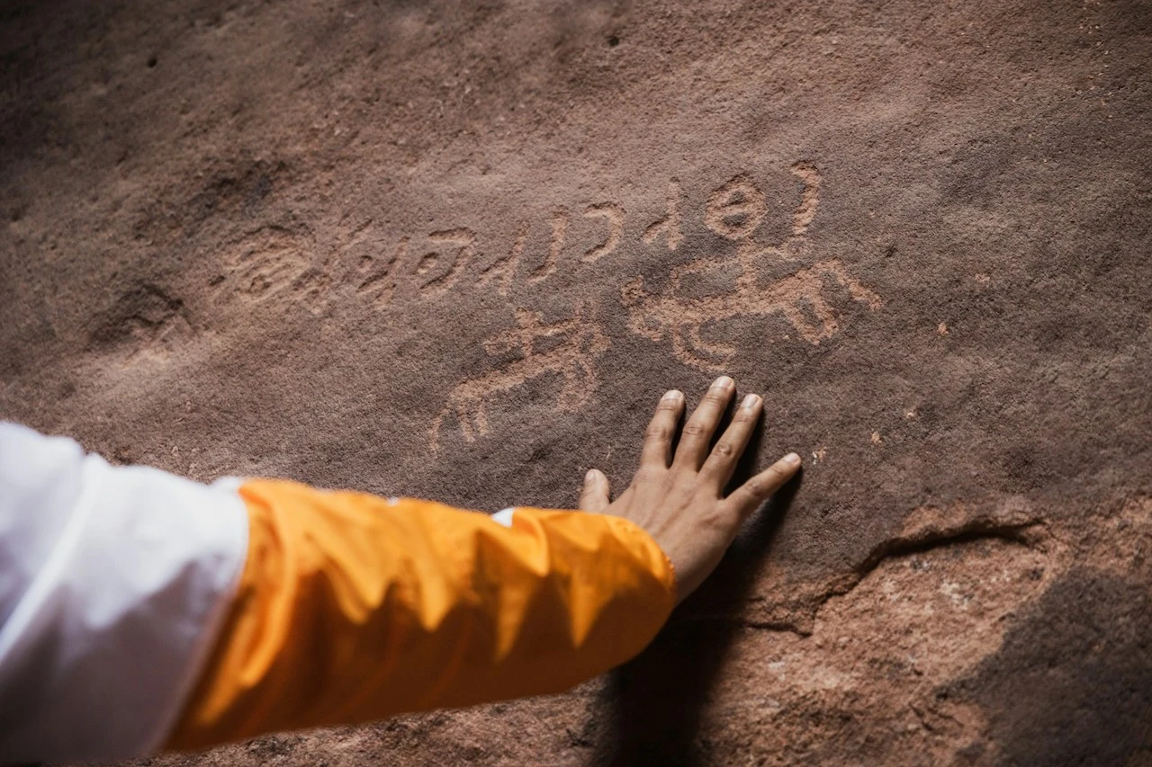 Inscrições rupestres em pedra avermelhada na Arábia Saudita, local de patrimônio histórico variado.