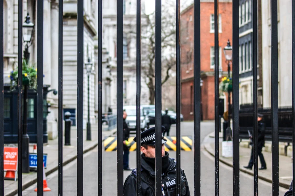 Foto mostra policial inglês atrás de um portão.