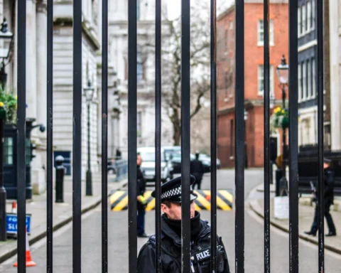 Foto mostra policial inglês atrás de um portão.